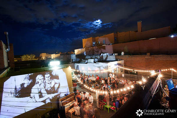 Outdoor urban wedding reception with a projected slideshow of drawings of the couple